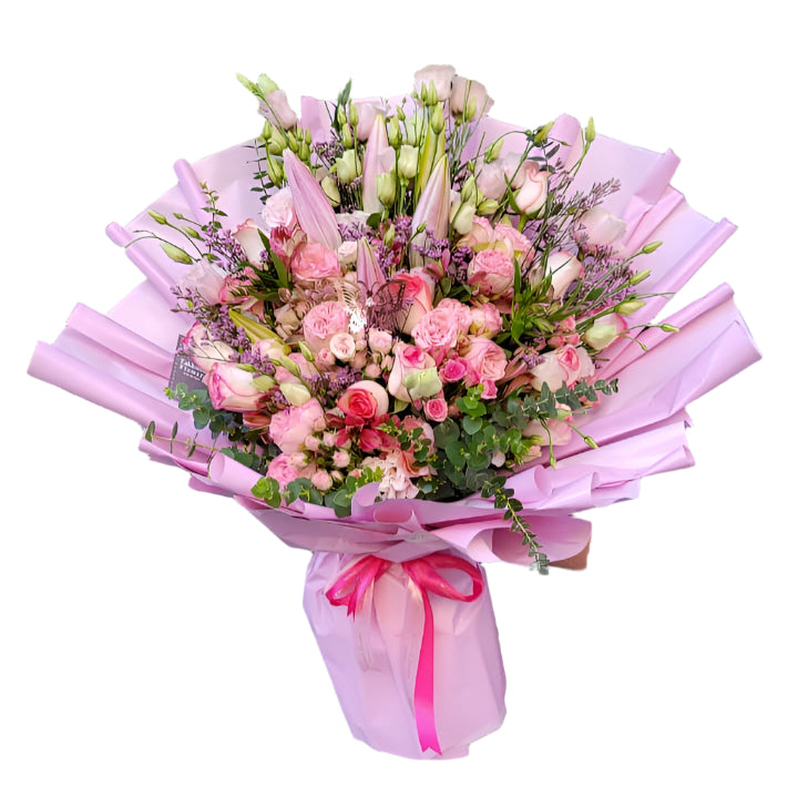 Large luxury bouquet wrapped in soft pink paper, featuring pink roses, lisianthus buds, oriental lilies, eucalyptus sprigs, and delicate filler blooms tied with a pink satin ribbon.