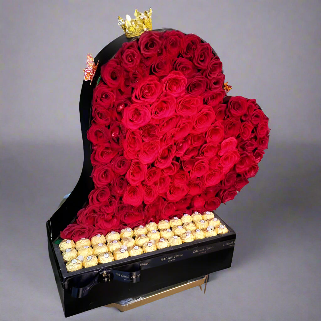 Luxury black box featuring a heart-shaped arrangement of red roses with Ferrero Rocher chocolates and a gold crown accent from Takkoush Flowers, Beirut.