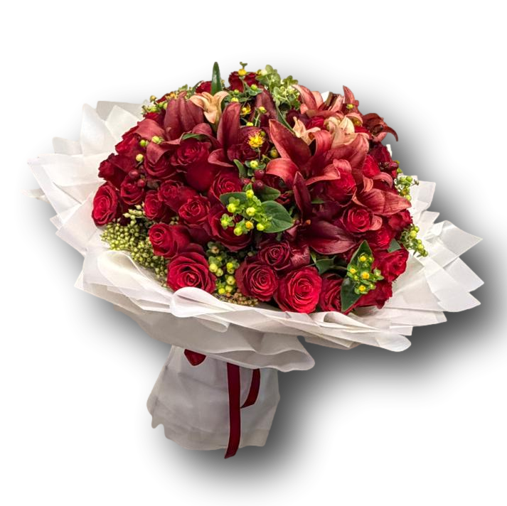 Luxurious mixed flower bouquet featuring red roses, deep red lilies, fresh greenery, and textured accents, wrapped in soft white layers, ideal for Valentine’s Day and elegant romantic gifting