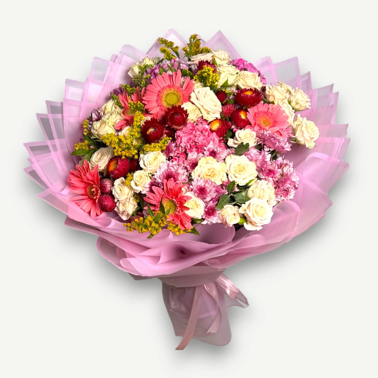 A vibrant mixed flower bouquet wrapped in pink tissue paper and tied with a matching pink ribbon, set against a plain light gray background.