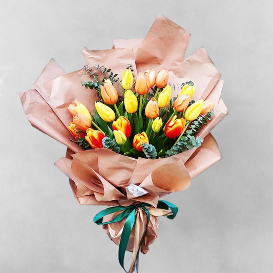 Celebrate the beauty of life with Sunny Smiles - 20 Tulip Bouquet. This stunning bouquet features a mix of ten red-yellow and ten yellow tulips, arranged in a way that showcases their vibrant hues and delicate petals. The bright colors of the tulips represent happiness and optimism, making this bouquet the perfect way to spread joy and bring a smile to someone's face. Ideal for any occasion that calls for a touch of happiness, Sunny Smiles is sure to make a lasting impression.